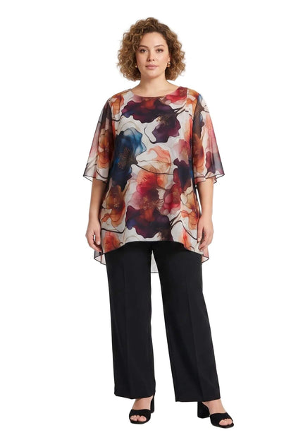 Ολόσωμη λήψη μιας plus size αέρινης σιφόν τουνίκ με πολύχρωμο φλοράλ μοτίβο σε λευκό φόντο, συνδυασμένης με μαύρη παντελόνα.