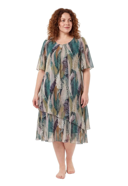 Ολόσωμη λήψη σε λευκό φόντο με plus size γυναίκα που φοράει αέρινο μίντι σιφόν φόρεμα με τροπικό σχέδιο σε πράσινες και μπεζ αποχρώσεις