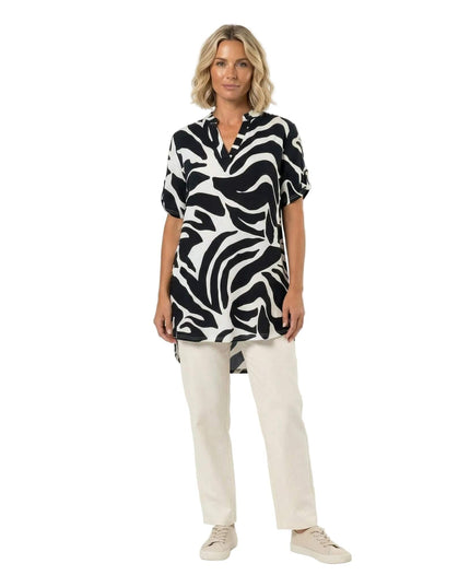 Ολόσωμη λήψη μοντέλου που φοράει ασύμμετρη ασπρόμαυρη τουνίκ σε μεγάλα μεγέθη. Ξεχωρίζει το αφηρημένο πριντ και η κομψή λαιμόκοψη V.