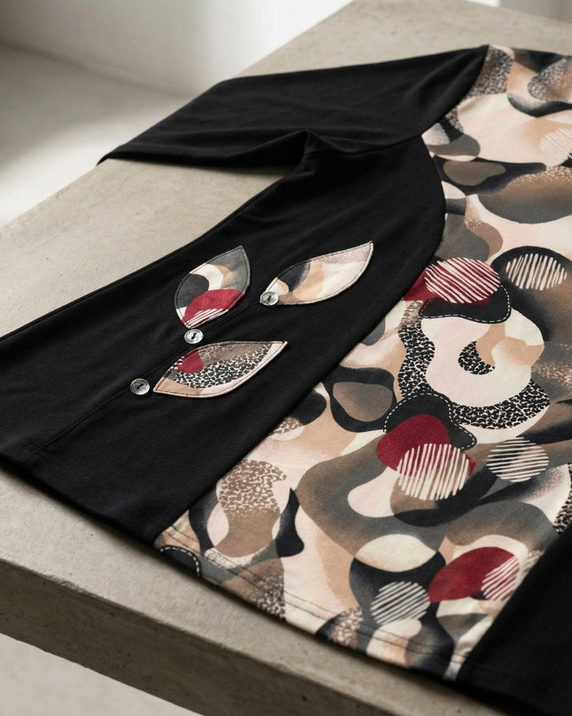 Детайлен кадър на елегантна черна туника с абстрактен цветен принт, акцентиращ върху декоративните апликации във форма на листа с копчета.