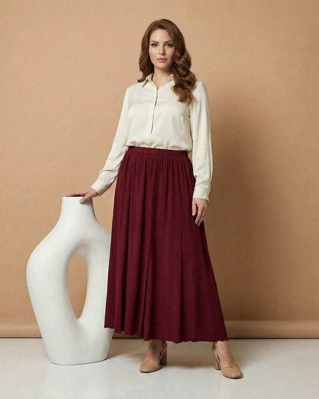 Επίσημη μπορντό εβαζέ φούστα σε μεγάλα μεγέθη, φορεμένη με κρεμ πουκάμισο. Ολόσωμη λήψη σε μπεζ φόντο, όπου αναδεικνύεται το ωραίο πέσιμο του ρούχου.