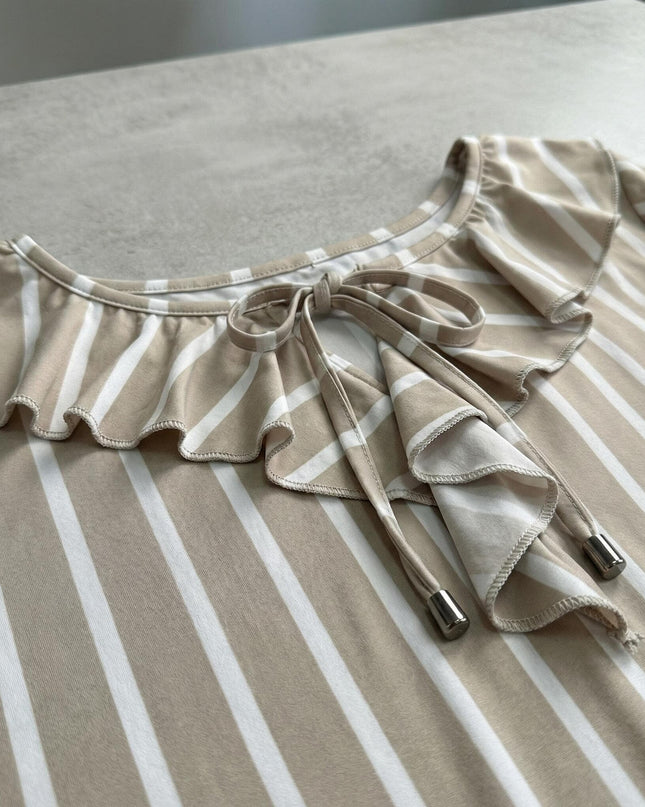 Κοντινή λεπτομέρεια του ντεκολτέ από επίσημη ριγέ τουνίκ σε μπεζ και λευκό χρώμα. Εμφανίζεται το σχέδιο με βολάν και κορδόνια στο λαιμό, κατάλληλο για μεγάλα μεγέθη.