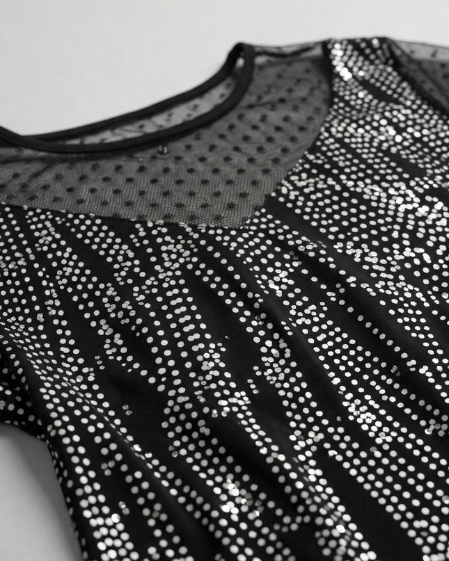 Κοντινή λήψη που εστιάζει στο ντεκολτέ επίσημης τουνίκ plus size, με μαύρο πουά τούλι στη λαιμόκοψη και ύφασμα διακοσμημένο με λαμπερή ασημοκλωστή.