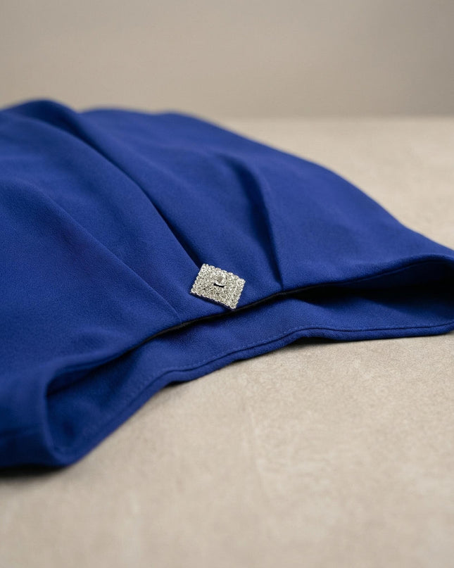 Κοντινή λεπτομέρεια από επίσημη μπλε ρουά τουνίκ σιφόν plus size, με έμφαση στη λαμπερή διακοσμητική καρφίτσα και την υφή του υφάσματος.