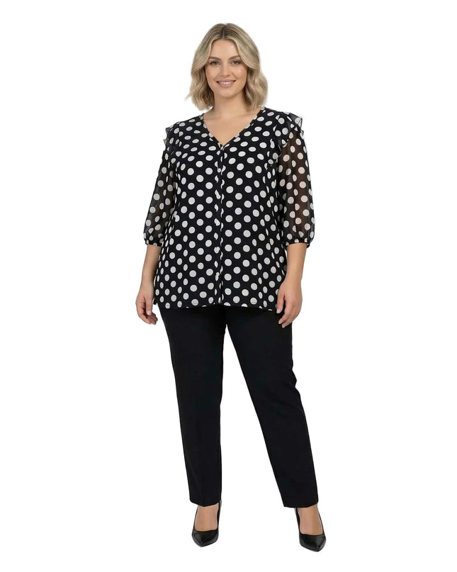 Ολόσωμη λήψη σε λευκό φόντο: Επίσημη γυναικεία σκούρα μπλε τουνίκ με λευκό πουά σε μεγάλα μεγέθη, φορεμένη με μαύρο παντελόνι.