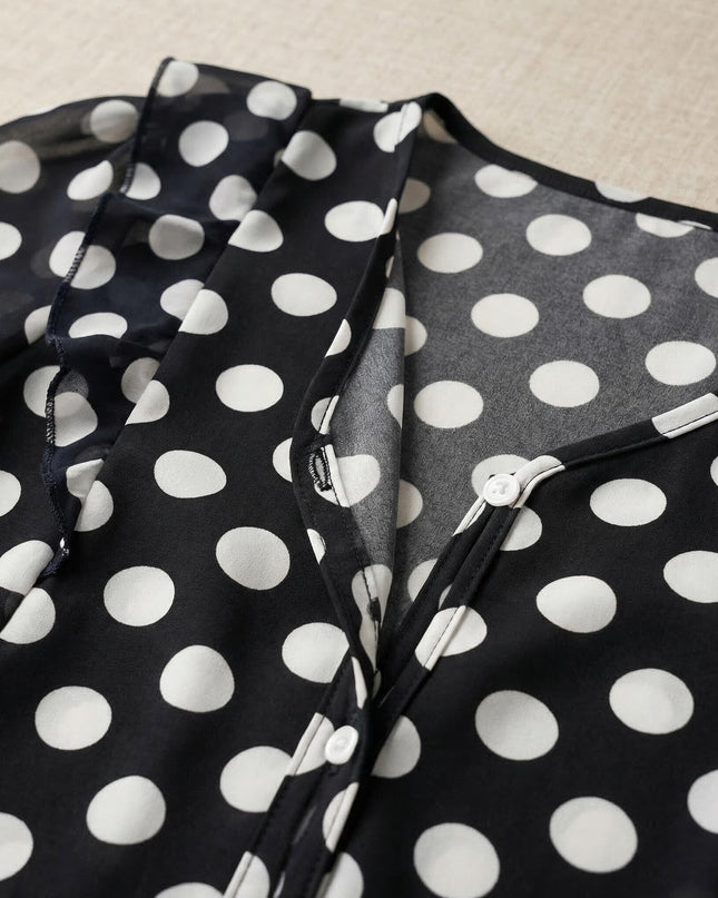 Κοντινή λεπτομέρεια από γυναικεία σκούρα μπλε τουνίκ σε μεγάλα μεγέθη, που αναδεικνύει το λευκό πουά, τη λαιμόκοψη V και τα μικρά λευκά κουμπιά.