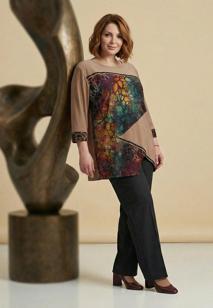 Επίσημη καφέ τουνίκ plus size με ασύμμετρη εμπριμέ φάσα και μανίκια 7/8. Ολόσωμη λήψη που παρουσιάζει τη ριχτή γραμμή και τον συνδυασμό με σκούρο παντελόνι.