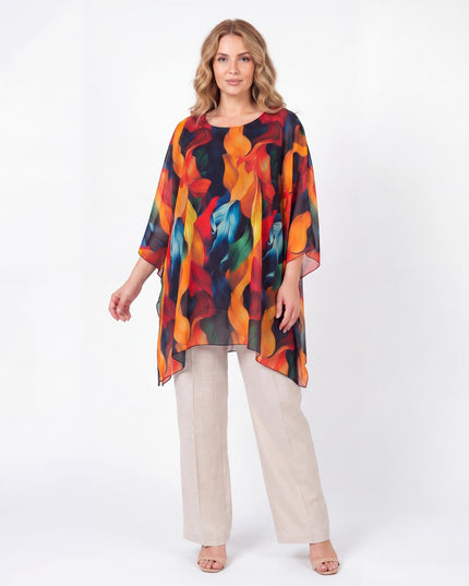 Ολόσωμη λήψη γυναίκας με επίσημη καλοκαιρινή μάξι τουνίκ πόντσο για μεγάλα μεγέθη, που αναδεικνύει το ζωηρό πολύχρωμο αφηρημένο μοτίβο της.