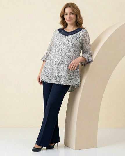 Ολόσωμη λήψη επίσημης λευκής φλοράλ τουνίκ σε μεγάλα μεγέθη, με κομψά μανίκια βολάν και διακοσμητικό τούλι με πέρλες στο ντεκολτέ.