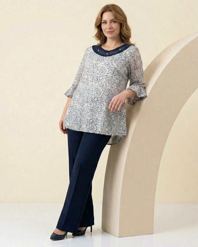 Ολόσωμη λήψη επίσημης λευκής φλοράλ τουνίκ σε μεγάλα μεγέθη, με κομψά μανίκια βολάν και διακοσμητικό τούλι με πέρλες στο ντεκολτέ.