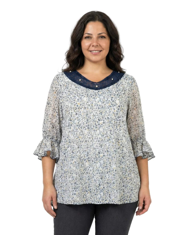 Επίσημη λευκή φλοράλ τουνίκ σε μεγάλα μεγέθη, σε μπροστινή λήψη. Διακρίνεται το ντεκολτέ με μπλε τούλι και πέρλες, καθώς και τα μανίκια με βολάν.