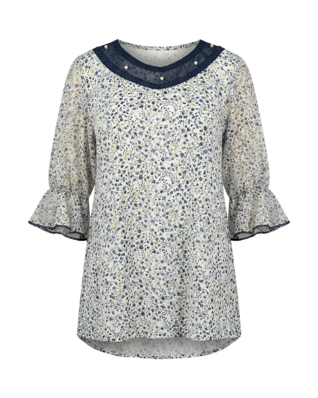 Επίσημη λευκή φλοράλ τουνίκ σε μεγάλα μεγέθη, με διακόσμηση από πέρλες και τούλι στο ντεκολτέ και μανίκια με βολάν, σε λευκό φόντο.