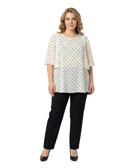 Επίσημη λευκή τουνίκ από σιφόν με μαύρο πουά και αέρινη εβαζέ γραμμή για μεγάλα μεγέθη, σε ολόσωμη λήψη με μαύρο παντελόνι.