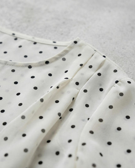 Κοντινή λήψη λεπτομέρειας από επίσημη λευκή τουνίκ σιφόν με μαύρο πουά μεγάλα μεγέθη, εστιάζοντας στις διακοσμητικές σούρες του ώμου και την ύφανση.