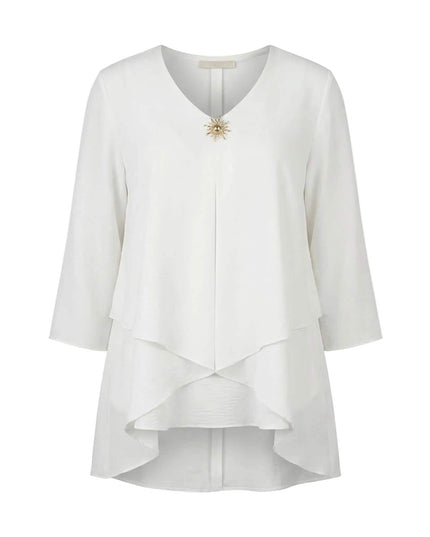 Επίσημη λευκή τουνίκ μεγάλα μεγέθη σε λευκό φόντο, με εντυπωσιακό ασύμμετρο τελείωμα σε επίπεδα, V-ντεκολτέ και κομψή χρυσή καρφίτσα.