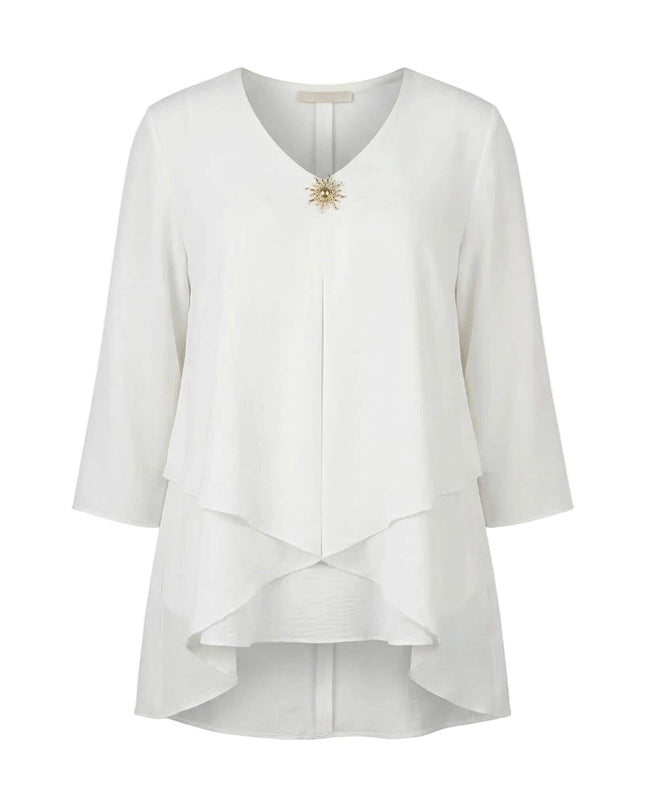 Επίσημη λευκή τουνίκ μεγάλα μεγέθη σε λευκό φόντο, με εντυπωσιακό ασύμμετρο τελείωμα σε επίπεδα, V-ντεκολτέ και κομψή χρυσή καρφίτσα.