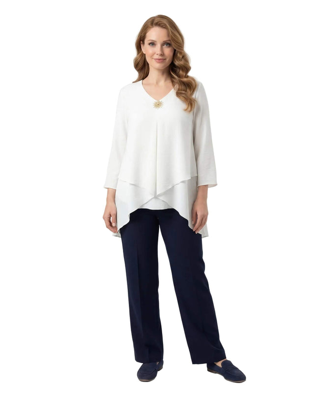 Επίσημη λευκή τουνίκ σε μεγάλα μεγέθη με V-ντεκολτέ, διακοσμητική καρφίτσα και ασύμμετρη γραμμή. Ολόσωμη λήψη που αναδεικνύει την εβαζέ εφαρμογή.