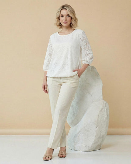 Ολόσωμη λήψη: Επίσημη λευκή τουνίκ σε μεγάλα μεγέθη, με ανάγλυφο φλοράλ σχέδιο και μανίκια 7/8, φορεμένη από μοντέλο με ανοιχτόχρωμο παντελόνι.