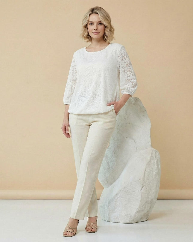 Ολόσωμη λήψη: Επίσημη λευκή τουνίκ σε μεγάλα μεγέθη, με ανάγλυφο φλοράλ σχέδιο και μανίκια 7/8, φορεμένη από μοντέλο με ανοιχτόχρωμο παντελόνι.