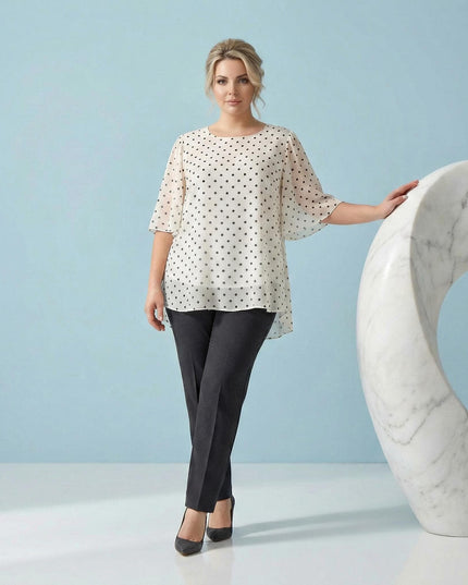 Αέρινη λευκή τουνίκ από σιφόν με μαύρο πουά, σχεδιασμένη για μεγάλα μεγέθη, σε ολόσωμη φωτογραφία μοντέλου με γαλάζιο φόντο.