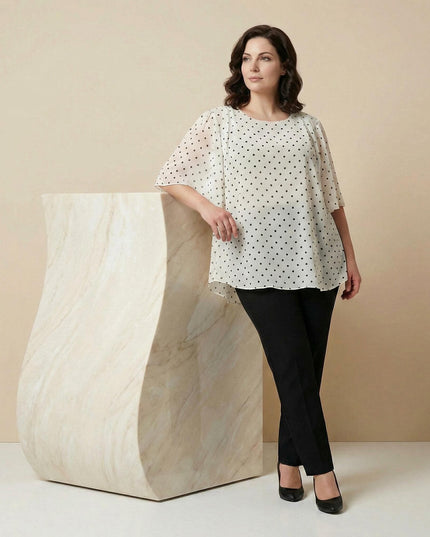 Επίσημη λευκή τουνίκ από αέρινο σιφόν με μαύρο πουά για μεγάλα μεγέθη, σε ολόσωμη λήψη με το μοντέλο να ποζάρει φορώντας μαύρο παντελόνι.