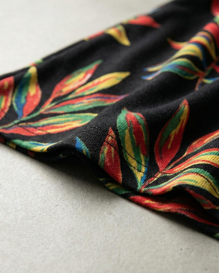 Κοντινή λεπτομέρεια από το ύφασμα επίσημης μαύρης τουνίκ μεγάλα μεγέθη, που αναδεικνύει το πολύχρωμο εμπριμέ σχέδιο με φύλλα και την ποιότητα της ραφής.