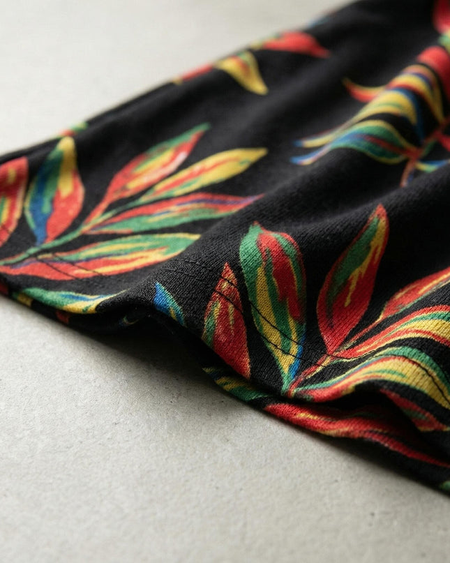 Κοντινή λεπτομέρεια από το ύφασμα επίσημης μαύρης τουνίκ μεγάλα μεγέθη, που αναδεικνύει το πολύχρωμο εμπριμέ σχέδιο με φύλλα και την ποιότητα της ραφής.