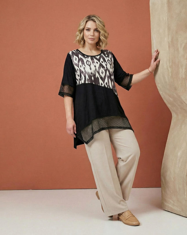 Επίσημη μαύρη τουνίκ μεγάλα μεγέθη σε ολόσωμη λήψη, με εντυπωσιακό αφηρημένο print, ασύμμετρο τελείωμα και λεπτομέρειες από δίχτυ.