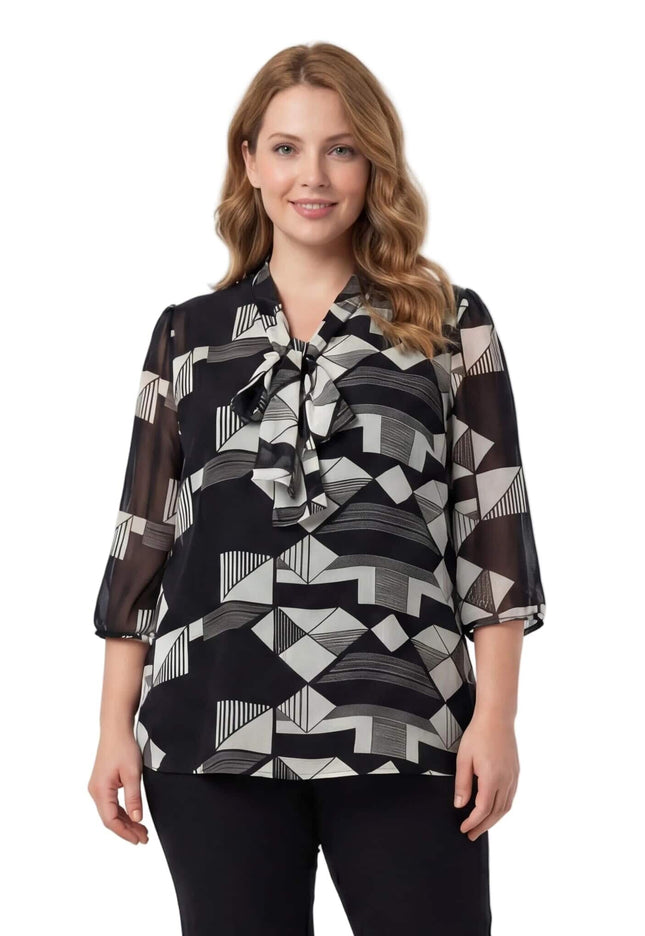 Επίσημη τουνίκ σε μεγάλα μεγέθη με γεωμετρικό μοτίβο σε μαύρο και λευκό, διακοσμητικό φιόγκο στο ντεκολτέ και αέρινα μανίκια, σε μπροστινή λήψη.