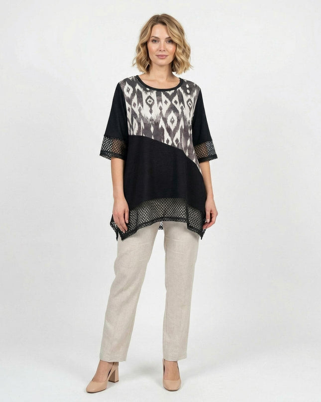 Ολόσωμη λήψη όπου μοντέλο φοράει επίσημη μαύρη τουνίκ μεγάλα μεγέθη με ασύμμετρη γραμμή, δίχτυ και αφηρημένο print μπροστά, σε λευκό φόντο.