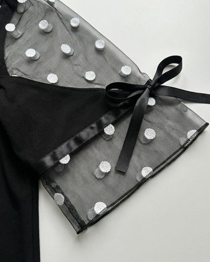 Κοντινή λεπτομέρεια μανικιού από επίσημη μαύρη τουνίκ plus size, με διάφανο τούλι, λευκές κεντητές βούλες και κομψό σατέν φιόγκο στο τελείωμα.