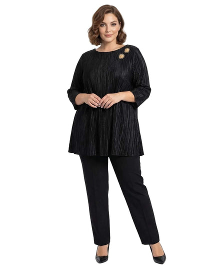 Ολόσωμη λήψη με γυναίκα να φοράει επίσημη μαύρη τουνίκ σε μεγάλα μεγέθη από πλισέ ύφασμα με μανίκια 7/8 και χρυσή καρφίτσα.