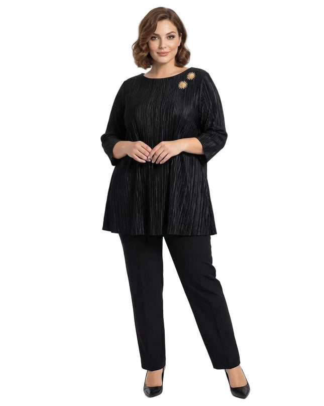 Ολόσωμη λήψη με γυναίκα να φοράει επίσημη μαύρη τουνίκ σε μεγάλα μεγέθη από πλισέ ύφασμα με μανίκια 7/8 και χρυσή καρφίτσα.