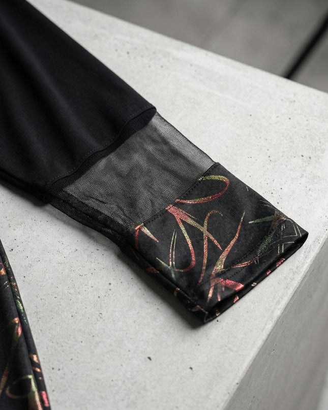 Κοντινή λεπτομέρεια στο μανίκι από επίσημη μαύρη τουνίκ σε μεγάλα μεγέθη, με διακοσμητική διαφάνεια και λαμπερό μοτίβο στο τελείωμα.