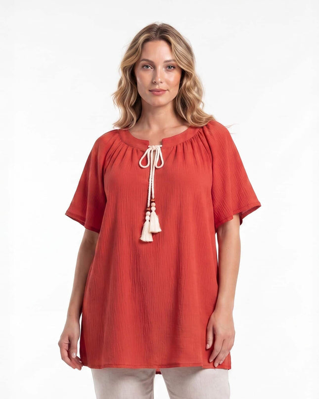 Επίσημη κεραμιδί τουνίκ σε μεγάλα μεγέθη με boho λευκά κορδόνια και φούντες στη λαιμόκοψη. Φωτογράφιση της μπροστινής όψης σε λευκό φόντο.