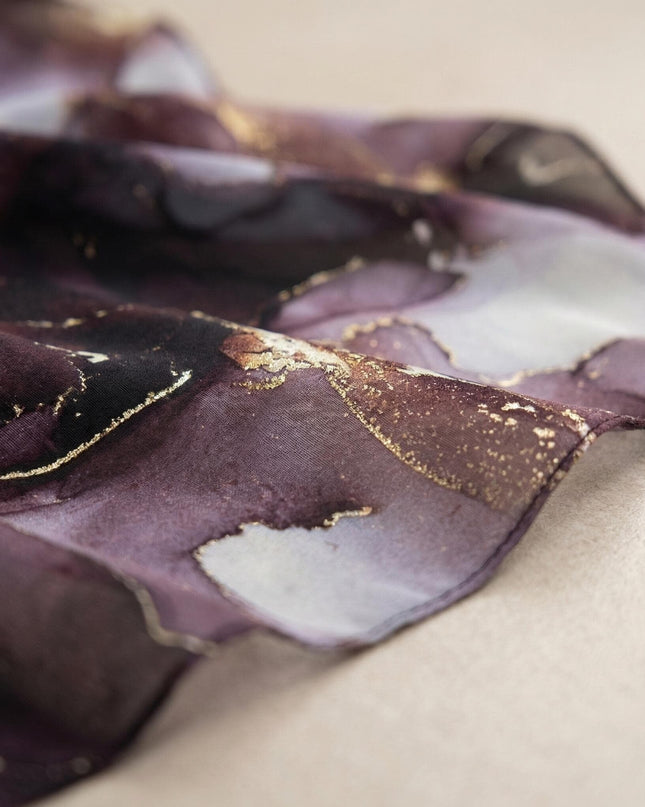 Κοντινή λεπτομέρεια στο μωβ σιφόν ύφασμα της επίσημης μάξι τουνίκ πόντσο. Διακρίνονται τα αφηρημένα σχέδια και οι χρυσές πινελιές. Για μεγάλα μεγέθη.