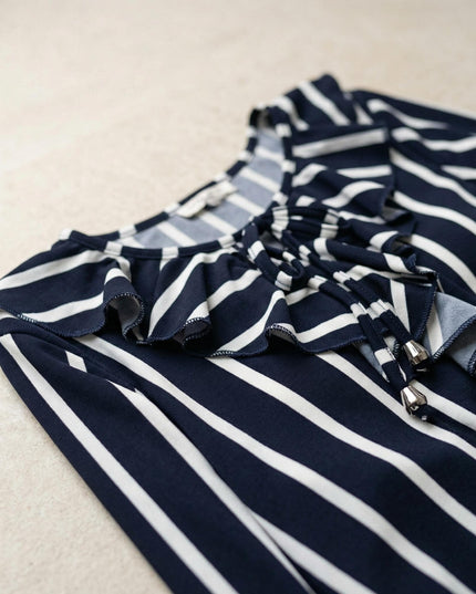 Κοντινή λεπτομέρεια λαιμόκοψης από επίσημη ριγέ τουνίκ σε μεγάλα μεγέθη, που αναδεικνύει το βολάν και τα κορδόνια με μεταλλικά στοιχεία.