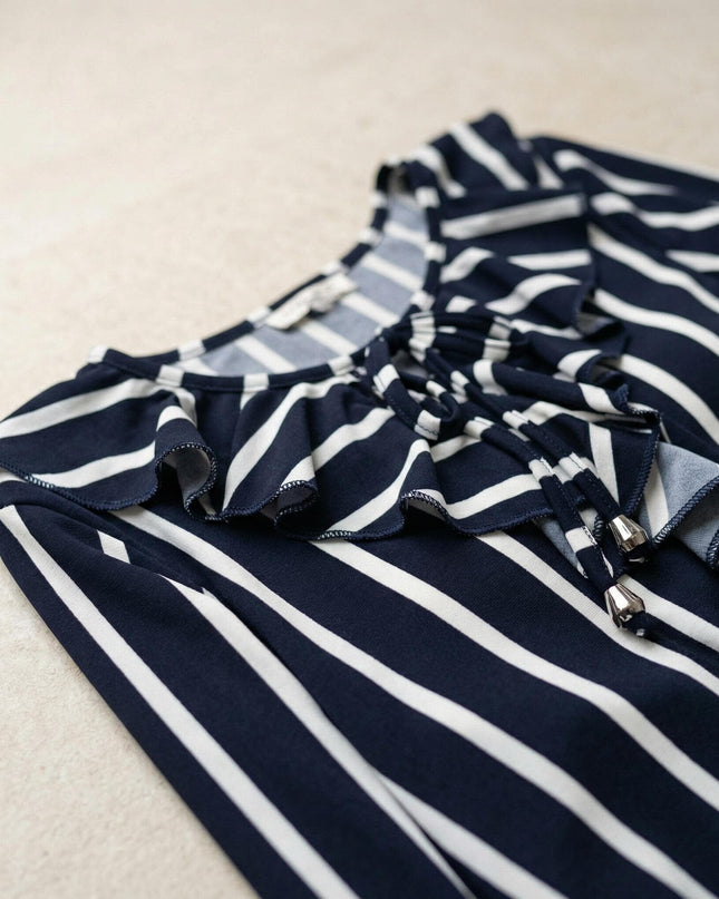 Κοντινή λεπτομέρεια λαιμόκοψης από επίσημη ριγέ τουνίκ σε μεγάλα μεγέθη, που αναδεικνύει το βολάν και τα κορδόνια με μεταλλικά στοιχεία.