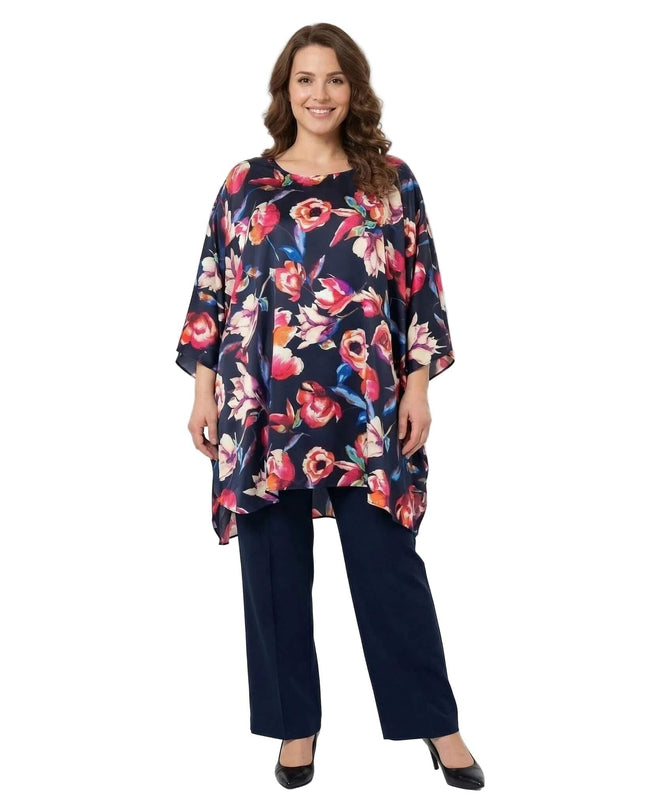 Ολόσωμη λήψη της επίσημης σκούρο μπλε φλοράλ τουνίκ πόντσο σε μεγάλα μεγέθη, φορεμένη με μπλε παντελόνι σε λευκό φόντο.