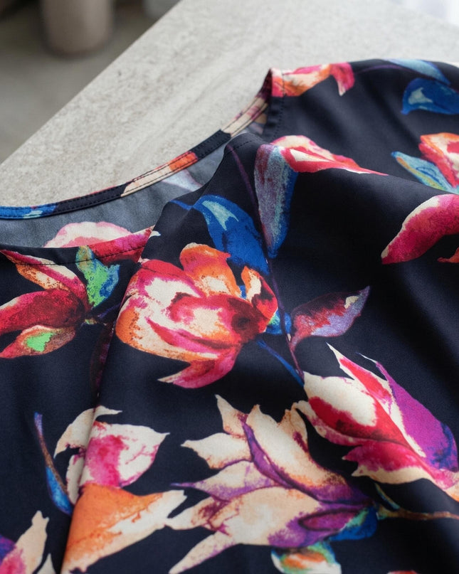 Κοντινή λεπτομέρεια από το σκούρο μπλε φλοράλ ύφασμα σε μάξι τουνίκ πόντσο για μεγάλα μεγέθη, αναδεικνύοντας τη λαιμόκοψη και το αέρινο σιφόν.