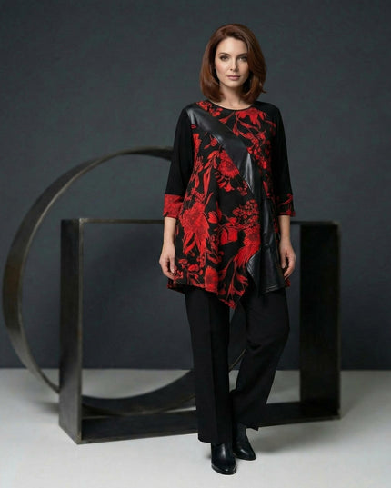 Επίσημη τουνίκ σε μεγάλα μεγέθη με κόκκινα λουλούδια και διαγώνια φάσα δερματίνης, σε ολόσωμη λήψη που αναδεικνύει την ασύμμετρη γραμμή.