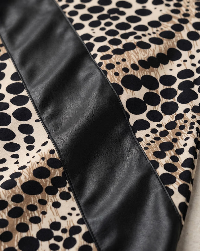 Κοντινή λεπτομέρεια υφάσματος σε τουνίκ μεγάλα μεγέθη: σύγχρονο λεοπάρ σχέδιο που συνδυάζεται με εντυπωσιακή διαγώνια φάσα από μαύρο οικολογικό δέρμα.