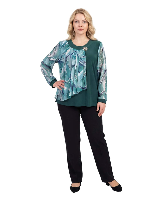 Επίσημη τουνίκ μεγάλα μεγέθη σε λαδί απόχρωση με ασύμμετρο φλοράλ σιφόν και καρφίτσα στο ντεκολτέ, σε ολόσωμη λήψη με μαύρο παντελόνι.