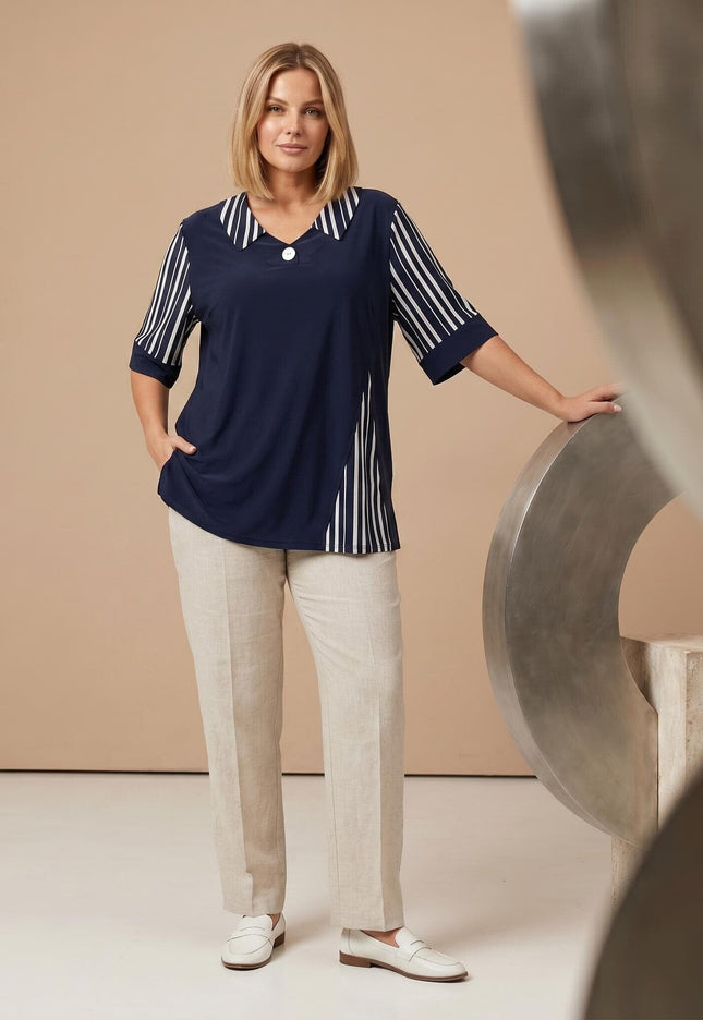 Ολόσωμη λήψη: Επίσημη σκούρο μπλε τουνίκ σε μεγάλα μεγέθη, με ασπρόμαυρες ριγέ λεπτομέρειες στο πλάι και τον γιακά, συνδυασμένη με μπεζ παντελόνι.