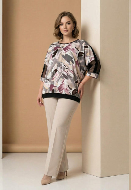 Επίσημη plus size τουνίκ με αφηρημένο πολύχρωμο μοτίβο και δίχτυ στα μανίκια. Ολόσωμη λήψη με το μοντέλο να φοράει μπεζ παντελόνι.