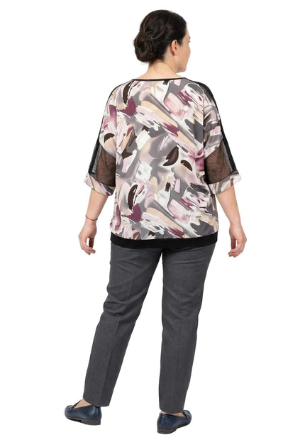 Πίσω όψη της επίσημης plus size τουνίκ με αφηρημένο μοτίβο και λεπτομέρειες από δίχτυ στα μανίκια, συνδυασμένη με γκρι παντελόνι.
