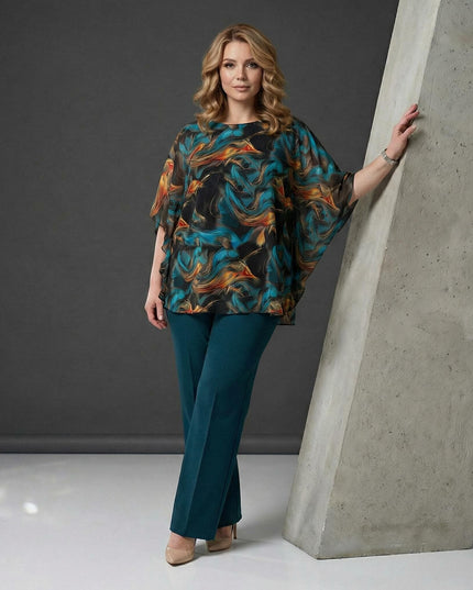 Επίσημη τουνίκ σιφόν σε μεγάλα μεγέθη με αφηρημένο σχέδιο σε τυρκουάζ και πορτοκαλί. Ολόσωμη λήψη του μοντέλου που συνδυάζει την μπλούζα με πετρόλ παντελόνι.