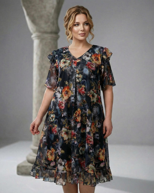 Επίσημο φλοράλ φόρεμα σιφόν σε μεγάλα μεγέθη, με μαύρη βάση και πολύχρωμα λουλούδια. Διαθέτει V λαιμόκοψη και βολάν στο τελείωμα, σε ολόσωμη λήψη.