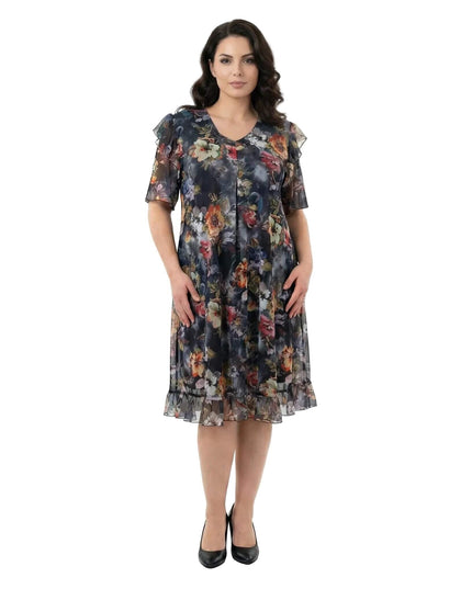 Επίσημο φλοράλ φόρεμα σιφόν σε μεγάλα μεγέθη με V λαιμόκοψη και βολάν στο τελείωμα, σε ολόσωμη φωτογραφία μπροστά σε λευκό φόντο.