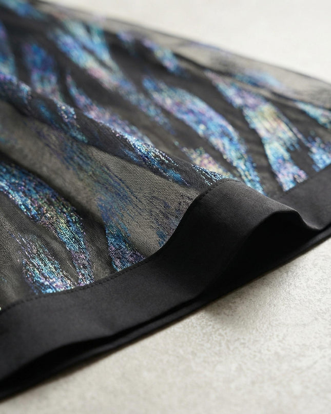 Κοντινή λεπτομέρεια από το τελείωμα σε επίσημο φόρεμα σιφόν plus size, που αναδεικνύει τα λαμπερά μπλε μοτίβα και τη φάσα δερματίνης.